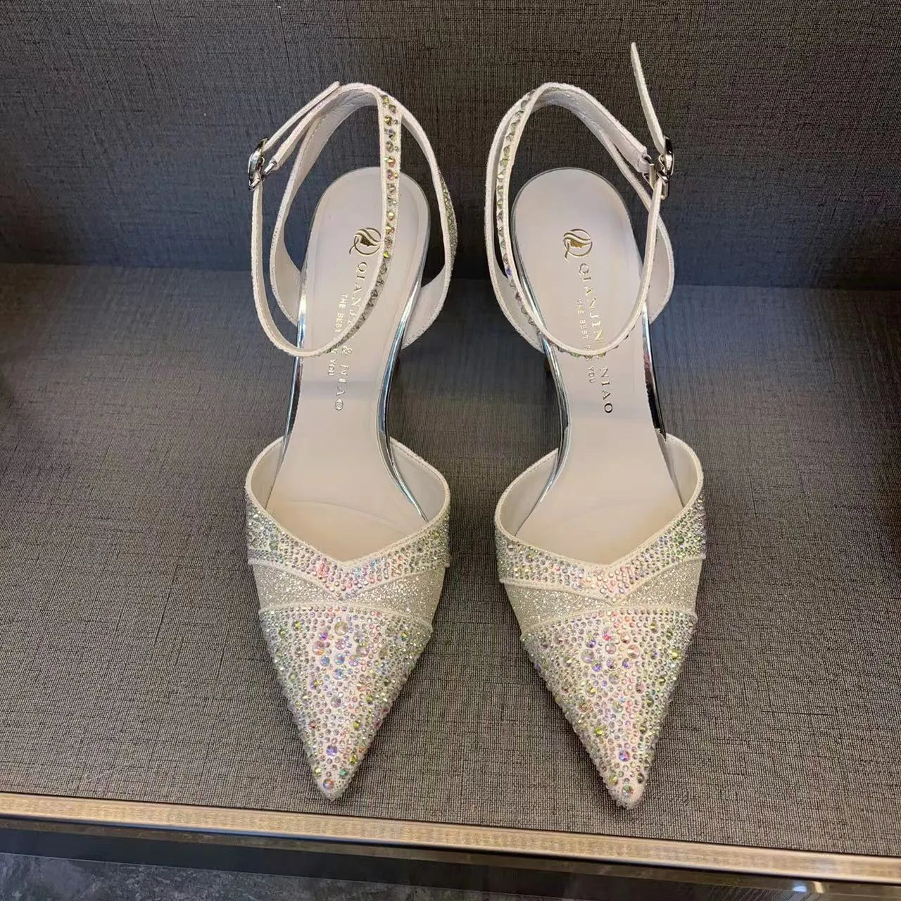 Women's silver high heels with hollow cut-out design and red stiletto heel sole.