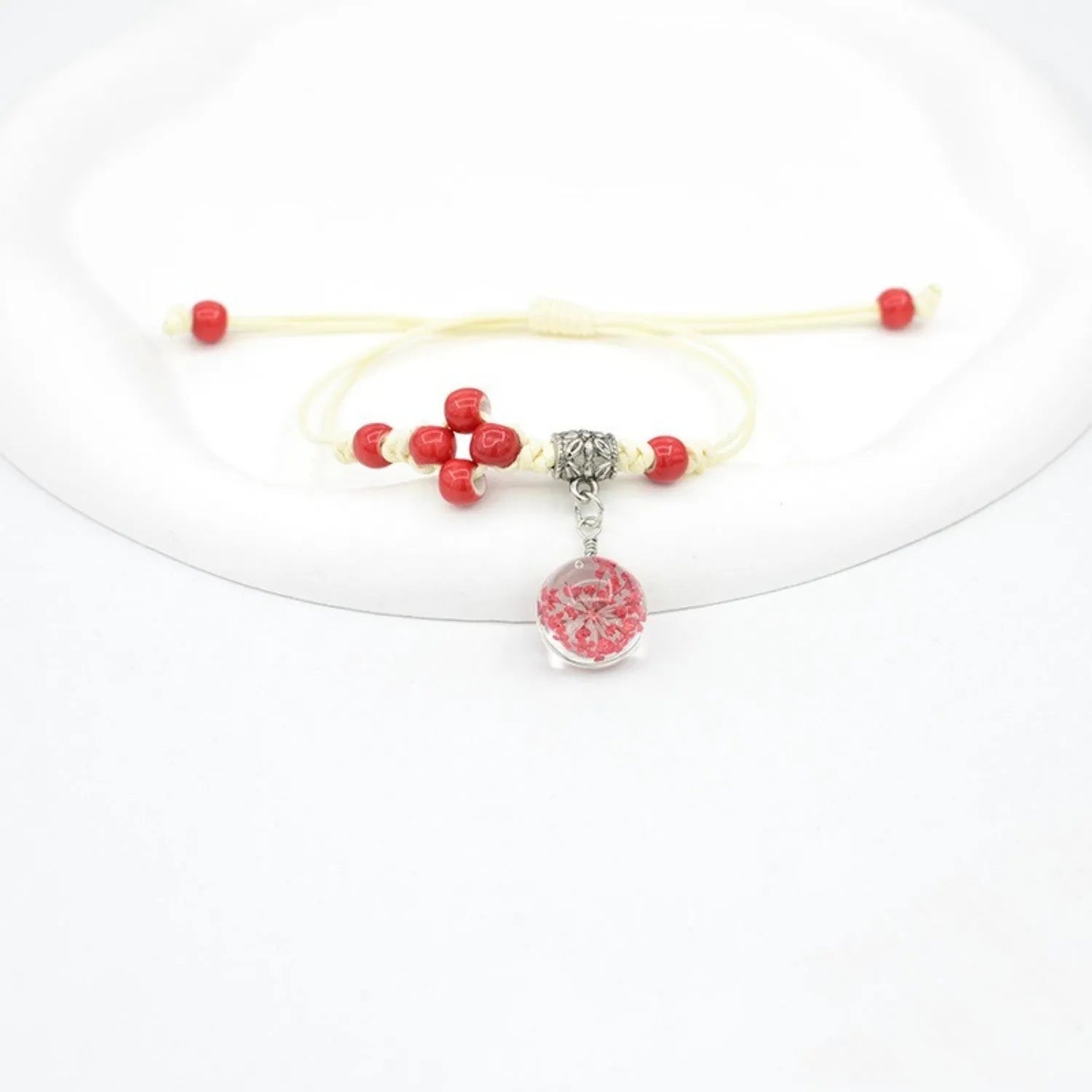 Glass bracelet with large colourful beads containing real dried flowers, on a white background.