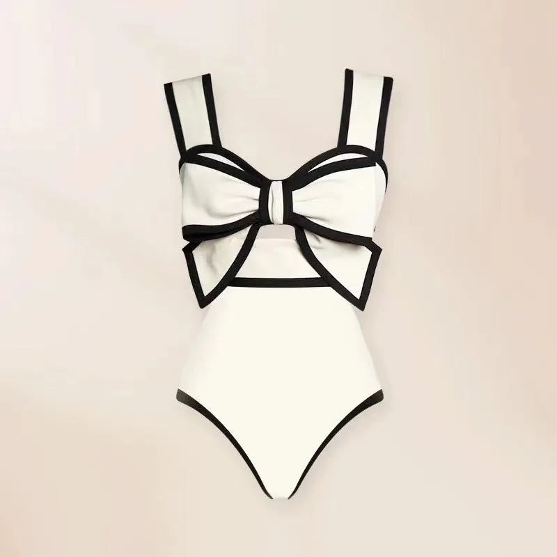 Women's black one-piece swimsuit with a white round skirt and a bow detail at the front.