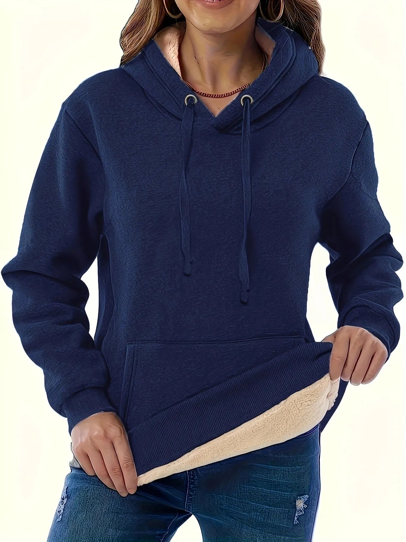 A woman wearing a loose thick black hooded sweater with side pockets and a 3D textured pattern.