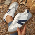 Blue women's low-top hiking shoes with flat rubber sole and lace-up front on artificial grass.