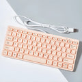 Compact USB wired keyboard in black, white, pink, or blue colour options on a desk.
