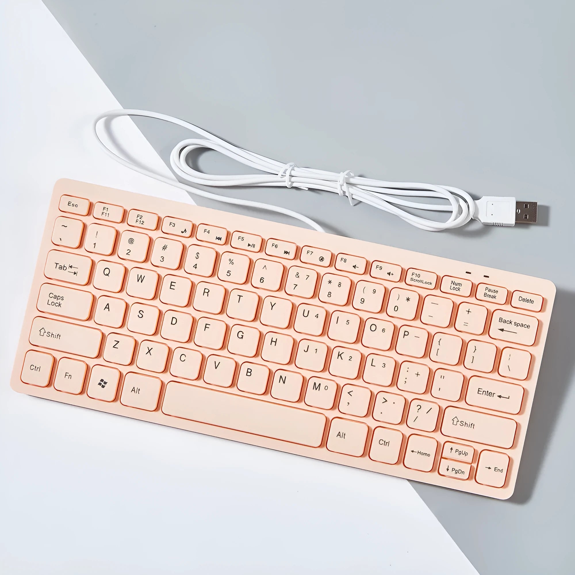 Compact USB wired keyboard in black, white, pink, or blue colour options on a desk.