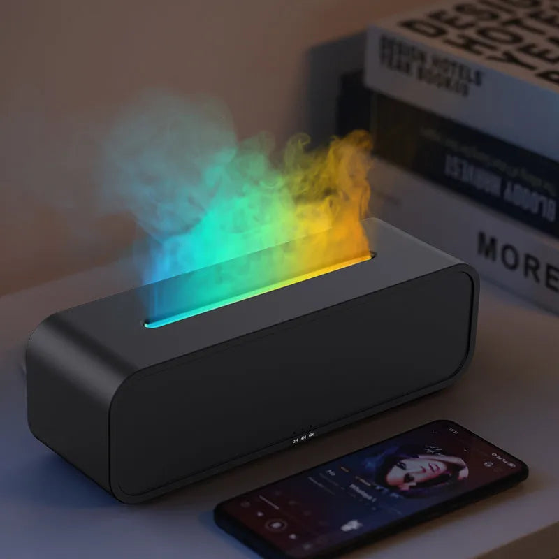 Black and white USB aroma diffuser with remote control on a desk, showing colour-changing LED lights.