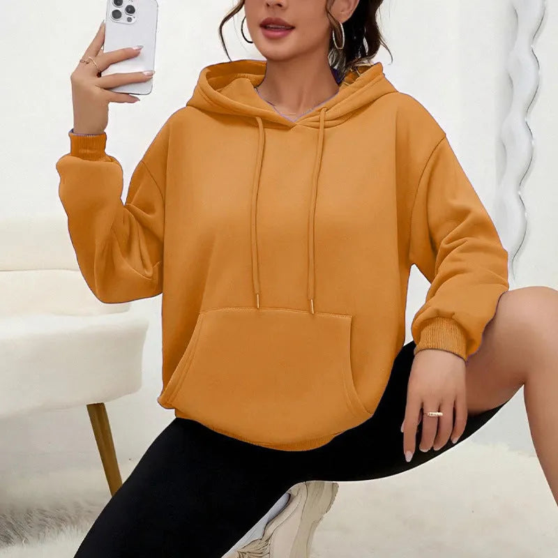 Woman wearing a loose grey drawstring waist sweatshirt with front pockets and long sleeves.