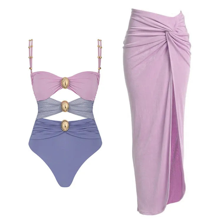Women's solid colour one-piece swimsuit with matching skirt and gold button detail.