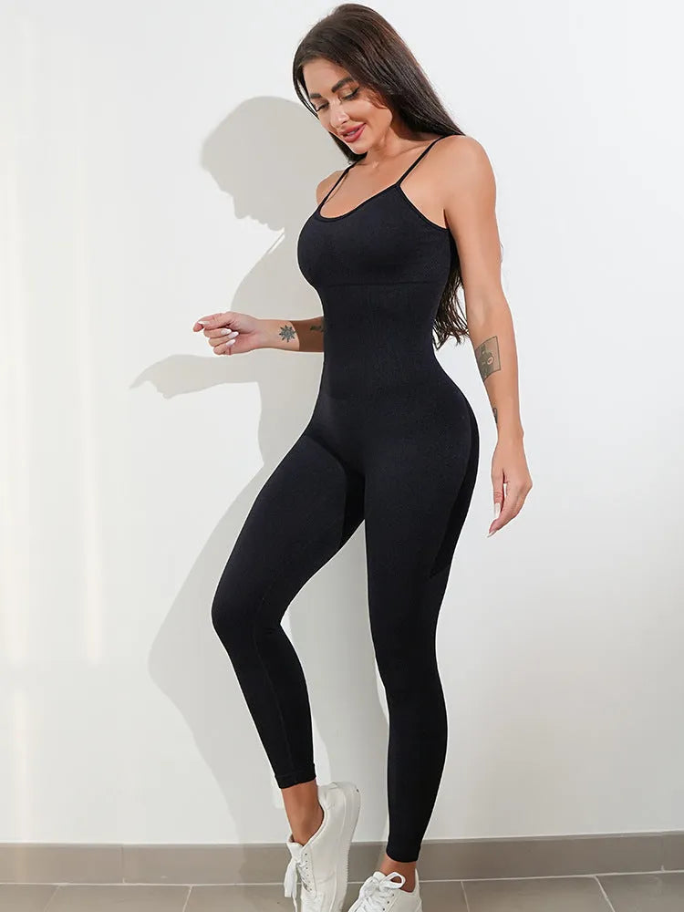 Woman wearing a black sleeveless unitard jumpsuit with spaghetti straps, showcasing the form-fitting tummy control design.