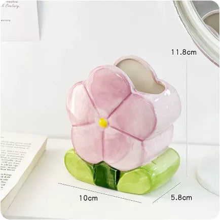 Ceramic pen holder box with floral pattern and lid on a wooden desk.