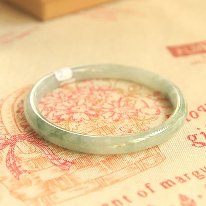 Green jade waxy geometric bracelet with Chinese-style design on a wrist.