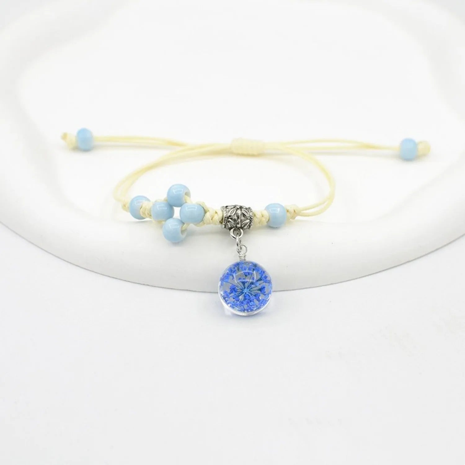 Glass bracelet with large colourful beads containing real dried flowers, on a white background.