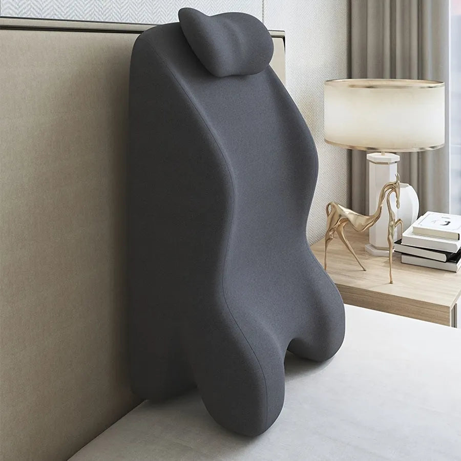 A stomach sleeper pillow shown in light grey, designed for reading or phone use in a prone position.