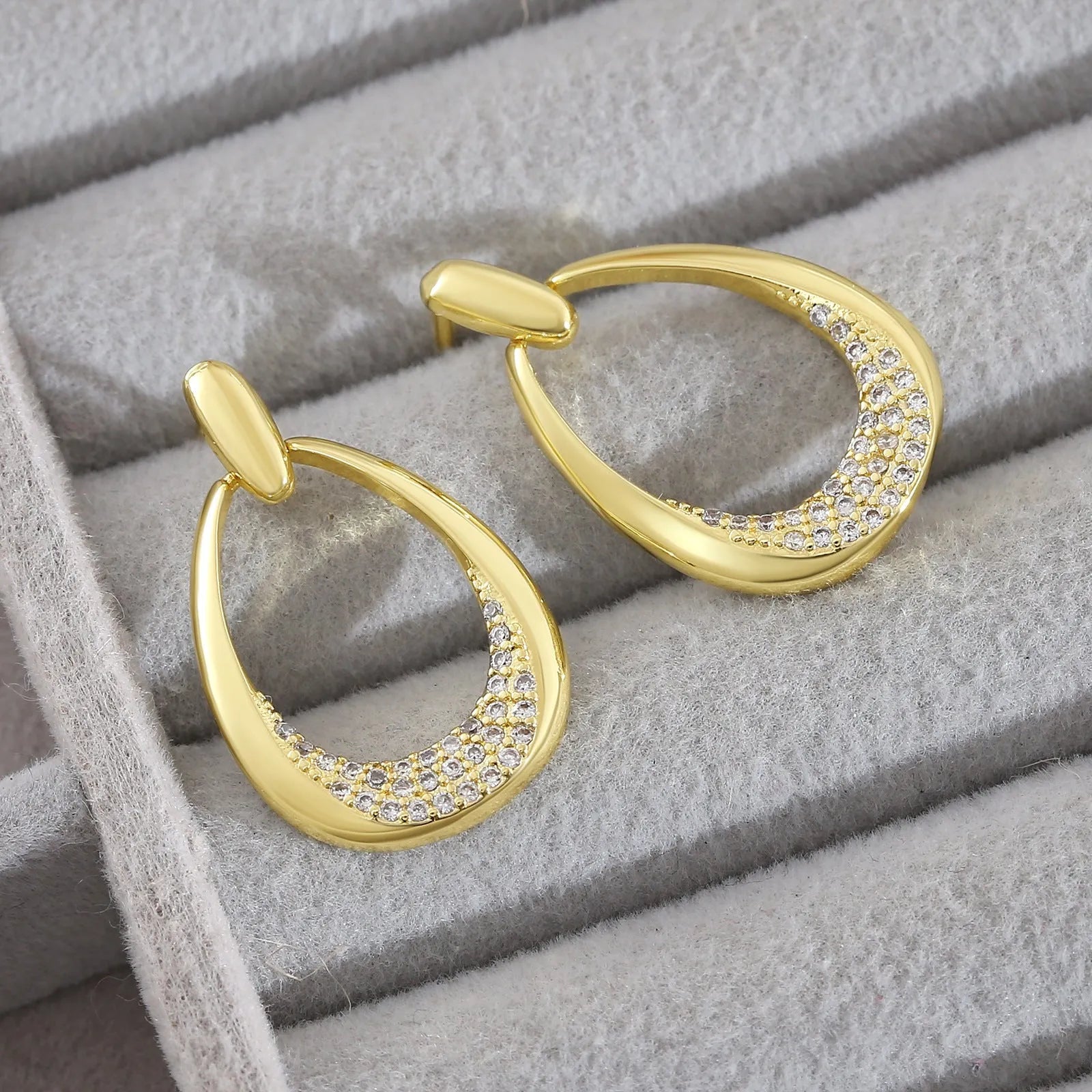 Yellow gold geometric drop earrings with oval and round ring elements on copper
