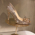Gold women's high heel with pointed toe, rhinestones, and a stiletto heel on a white background.