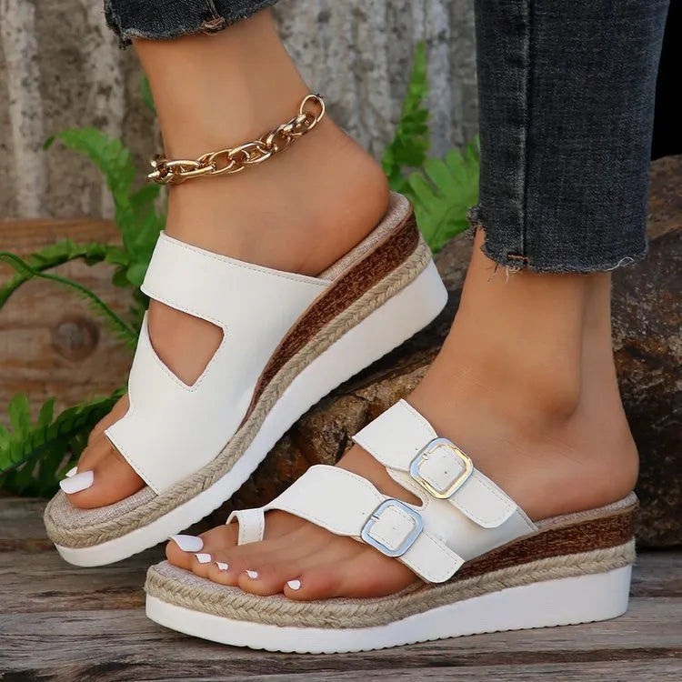 White patent leather woven wedge sandals with a peep toe and finger fit design on a neutral background.