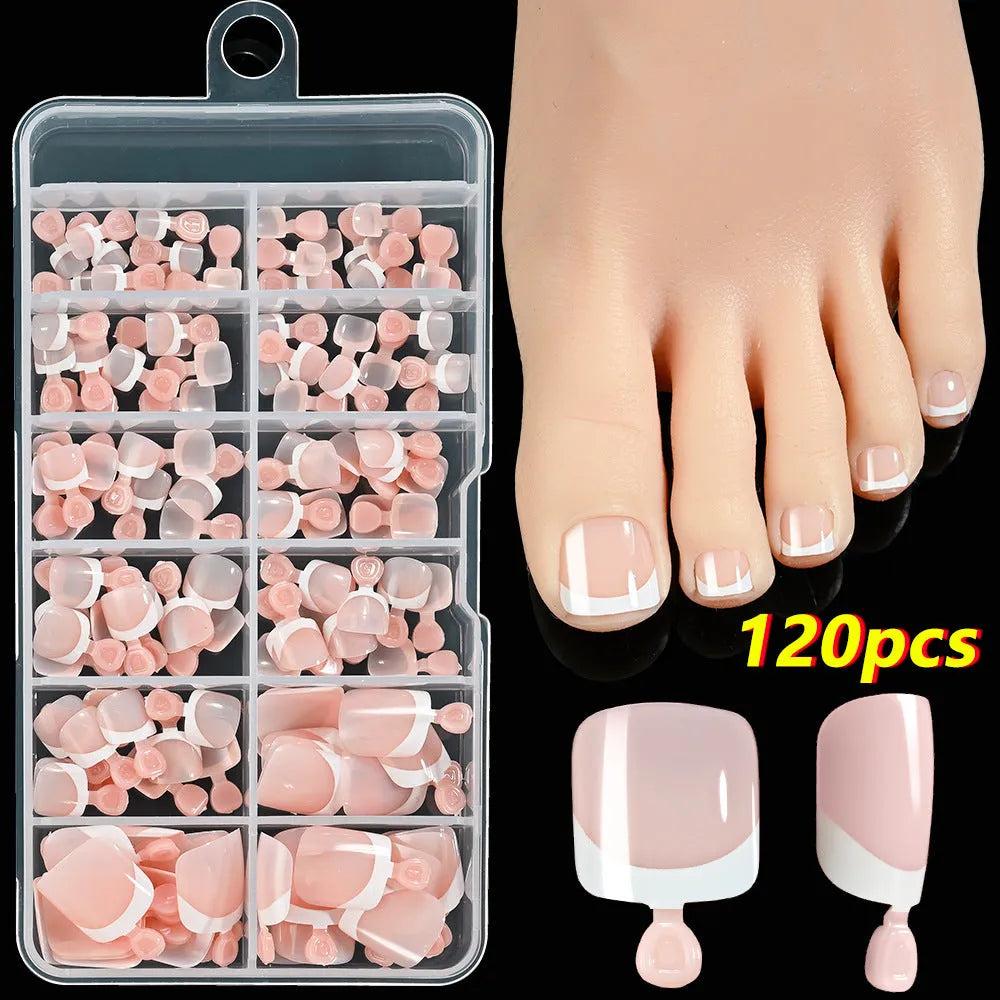 Box of 120 French white edge nude false toe nail pieces in assorted shades on a table