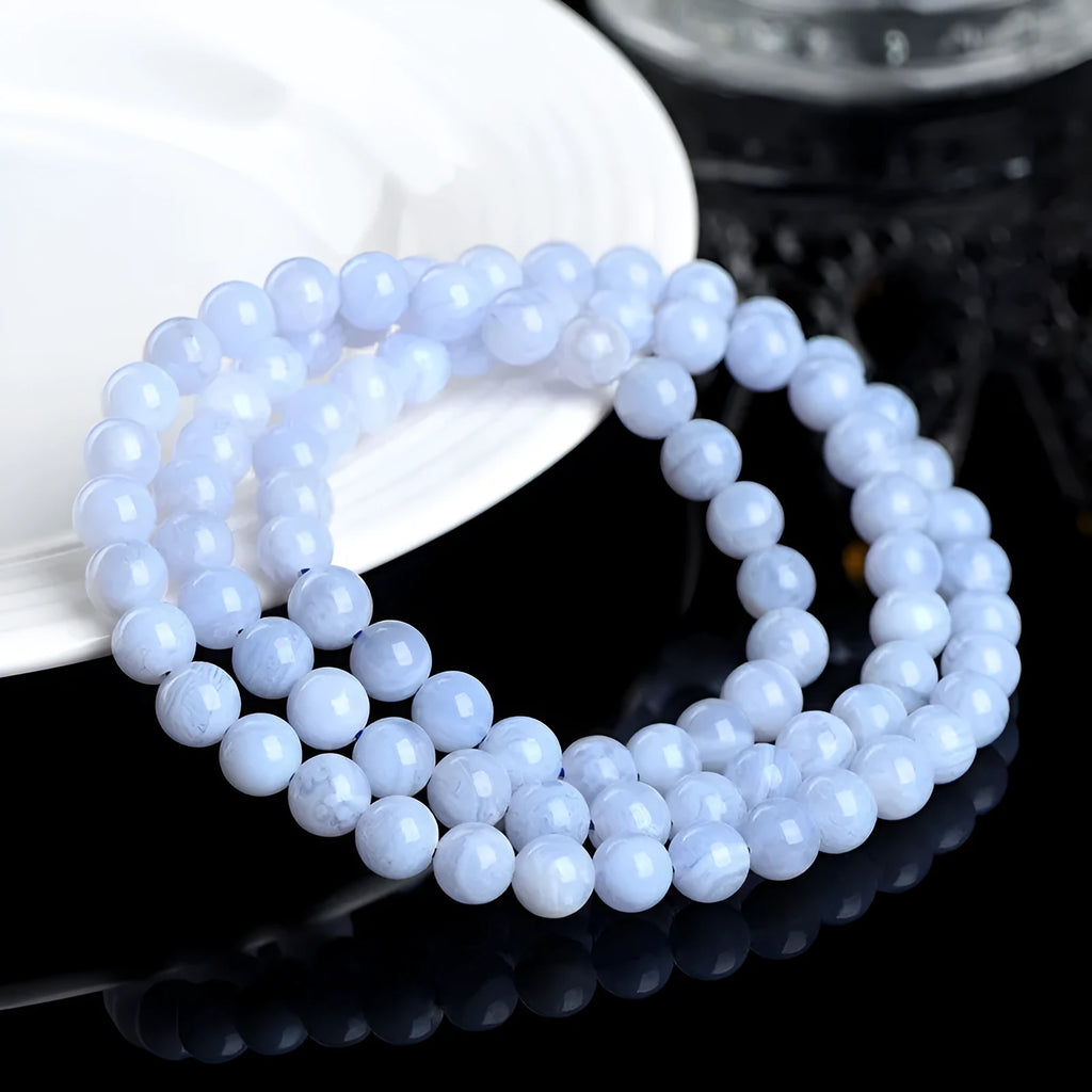 Blue agate bracelet with scattered beads pattern and a Ruyi charm on a white background.