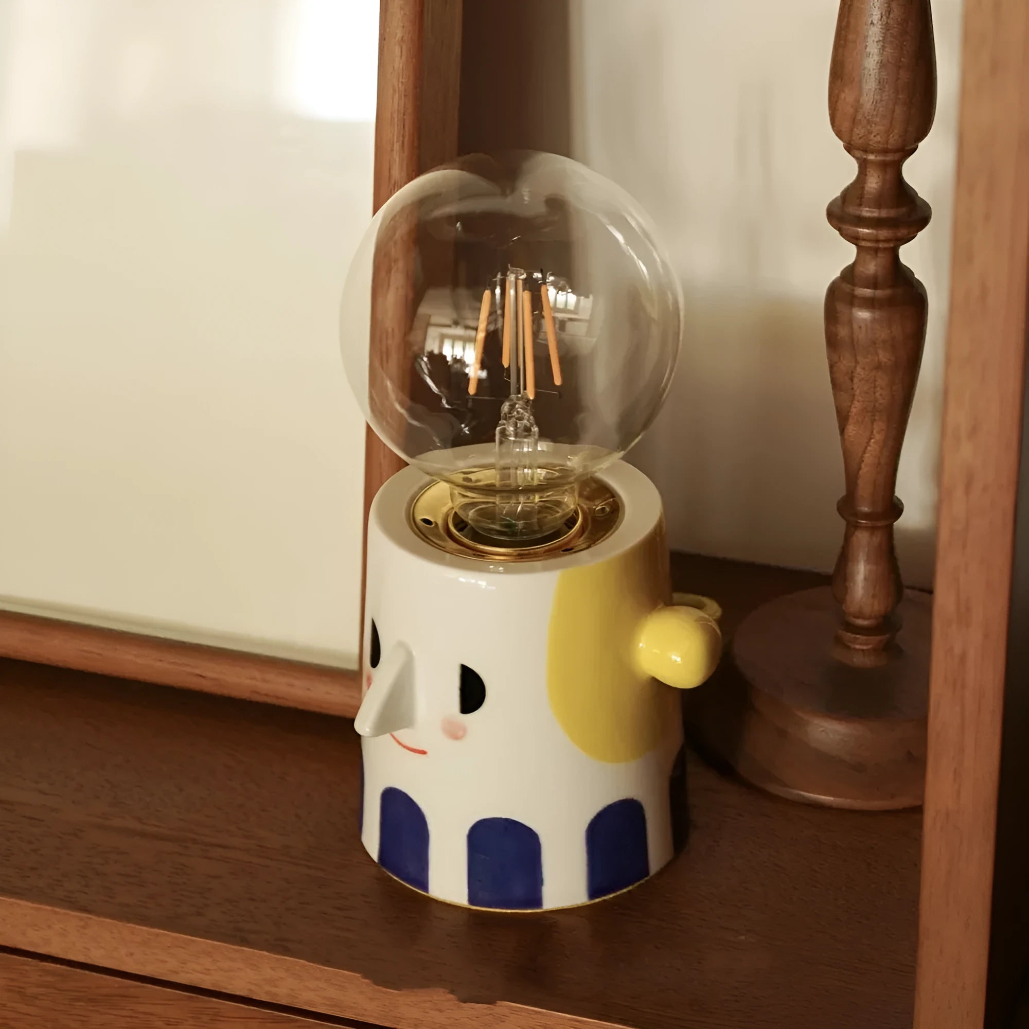 Handmade ceramic table lamp with a spherical ball headlight design on a bedside table.