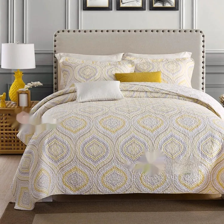 Quilted pure cotton bed cover set with printed pattern on a bed, includes two matching pillowcases.