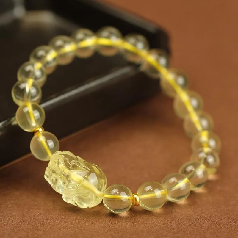 Yellow leather cord bracelet with artificial crystal beads and a Pi Xiu charm in Chinese folk style.