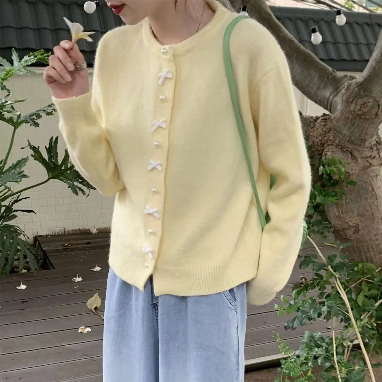 Women's cashmere cardigan sweater with bow and pearl buttons across chest in light blue colour