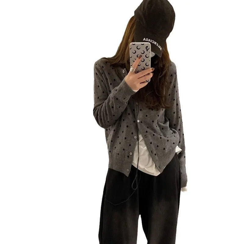 Women's loose fit grey knitted cardigan with crocheted flower details on the front.