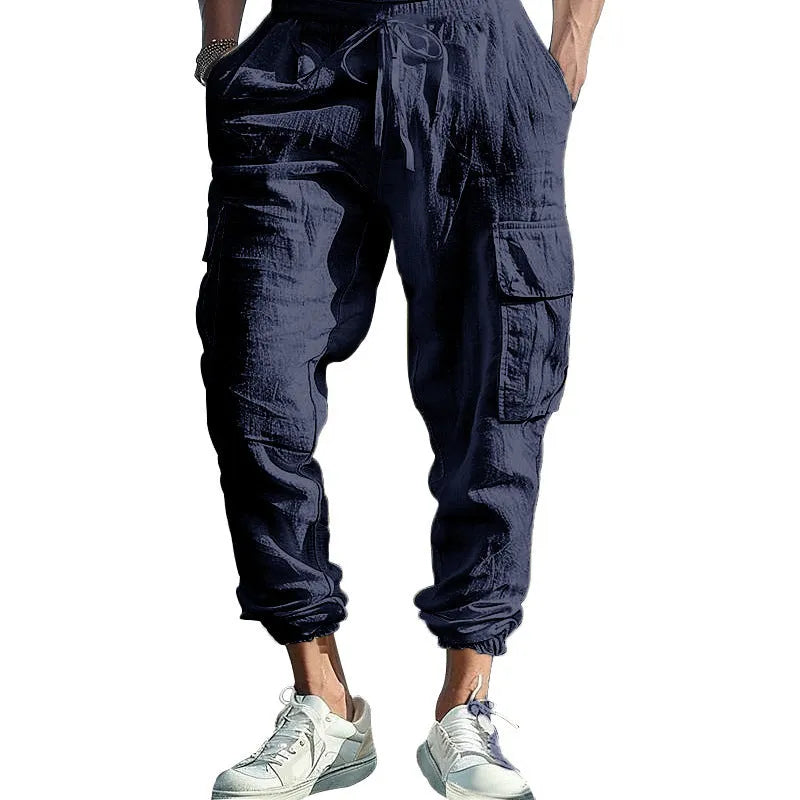 Man wearing loose-fit linen casual trousers with ankle-tied cuffs and multiple pockets in a solid colour.