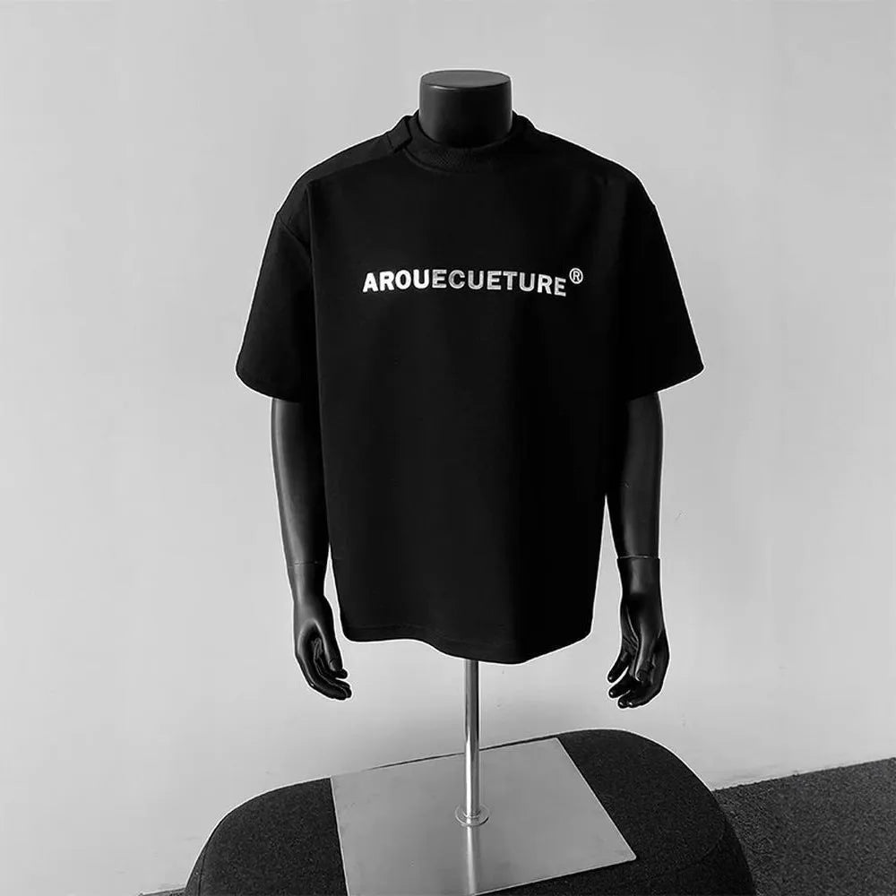 Men's loose fit cotton t-shirt with short sleeves and a printed letter design in light grey.