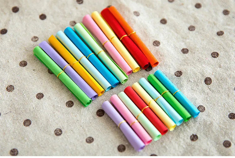 Assortment of colourful mini paper scrolls with metal eyelets in various sizes.