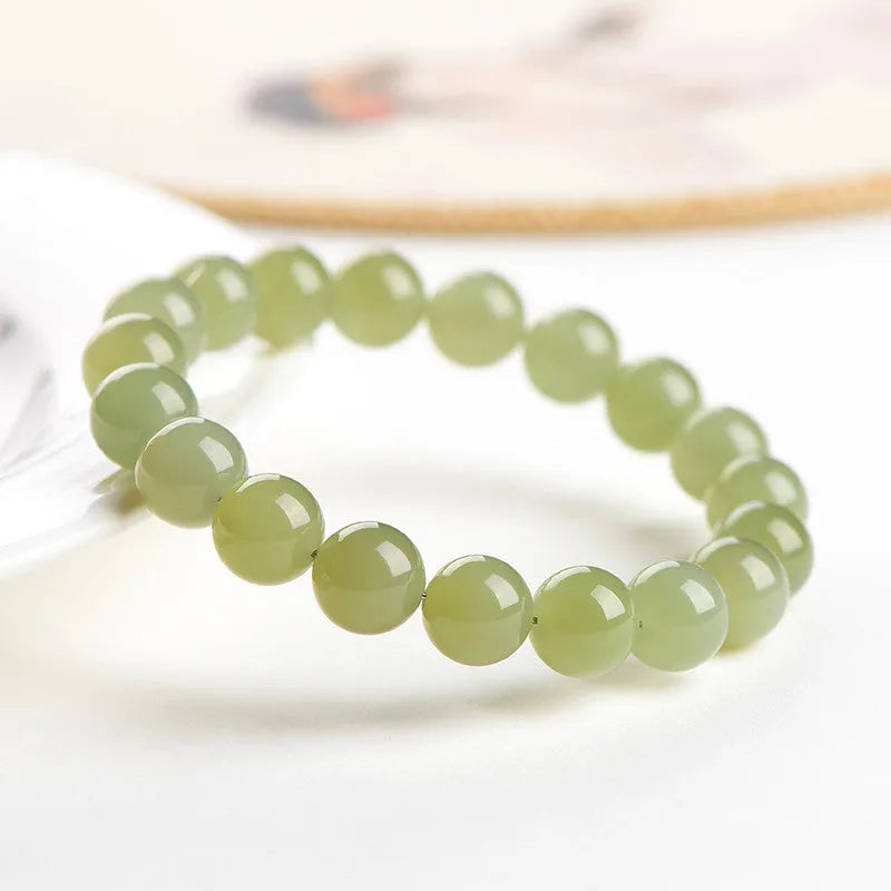 Polished Hetian jade ball bracelet on a wrist, showing ice-like clear beads in one of four available sizes.