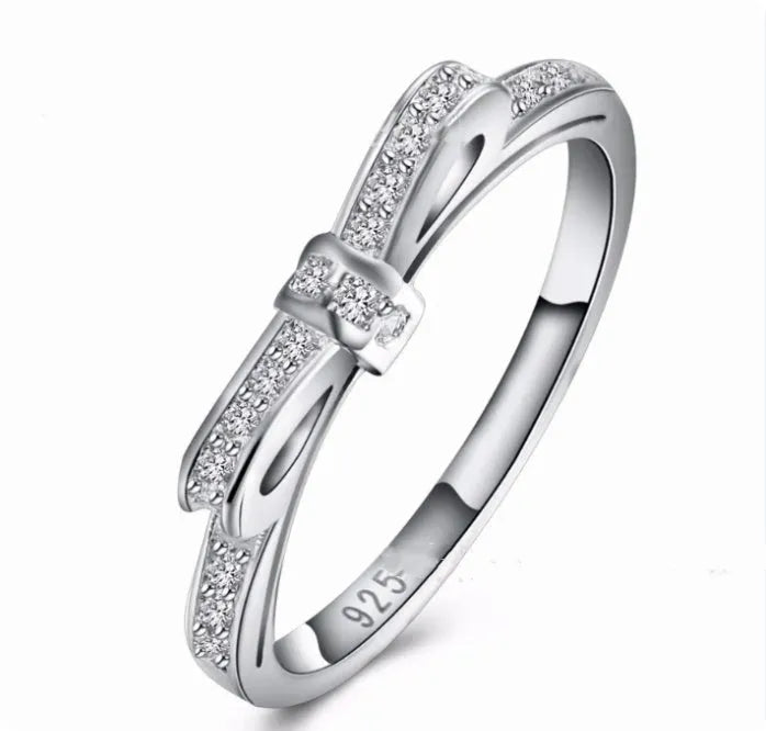 Silver bow-shaped ring with rhinestone zircon crystal detailing showing side profile view