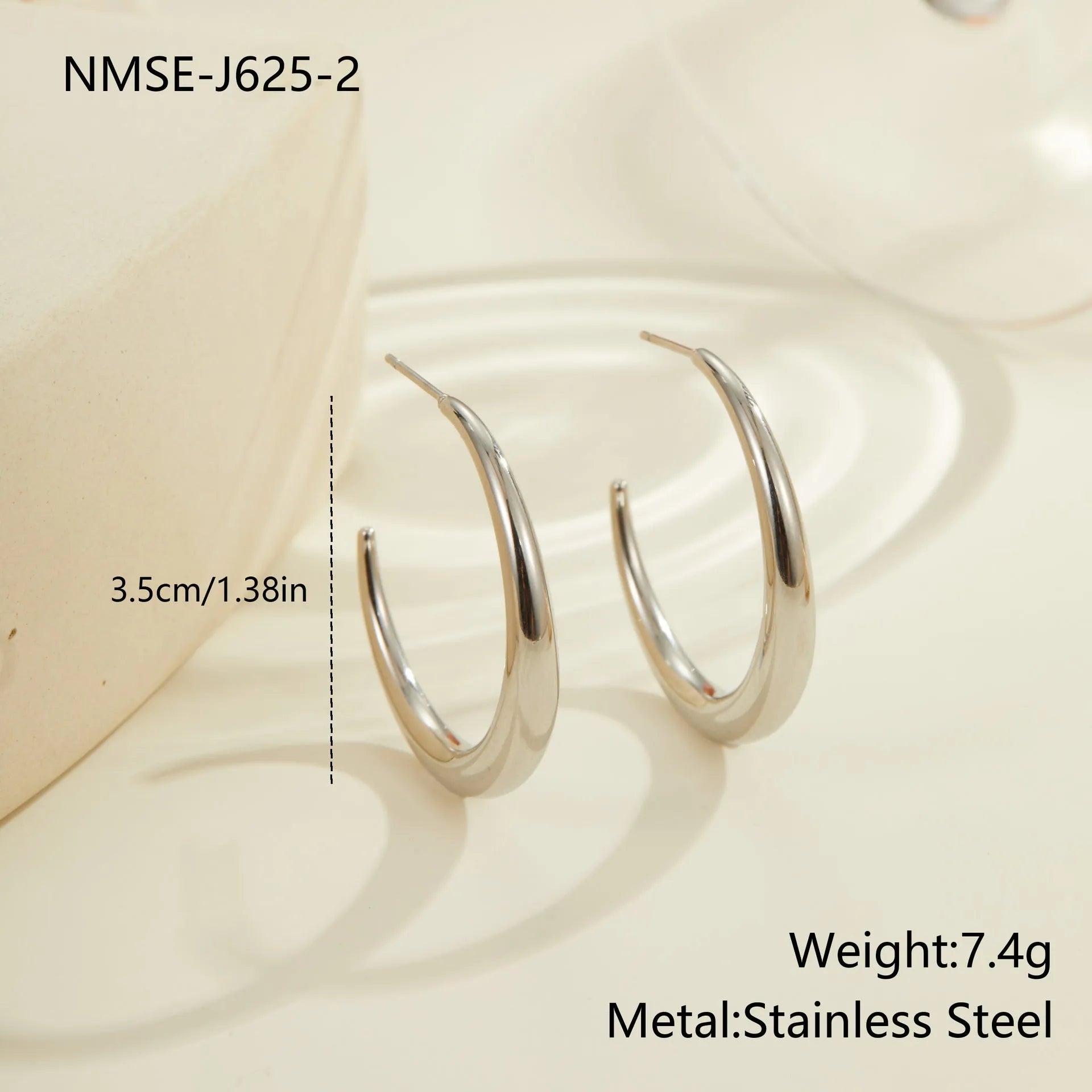 A pair of simple round titanium steel hoop earrings in a gold finish on a white background.