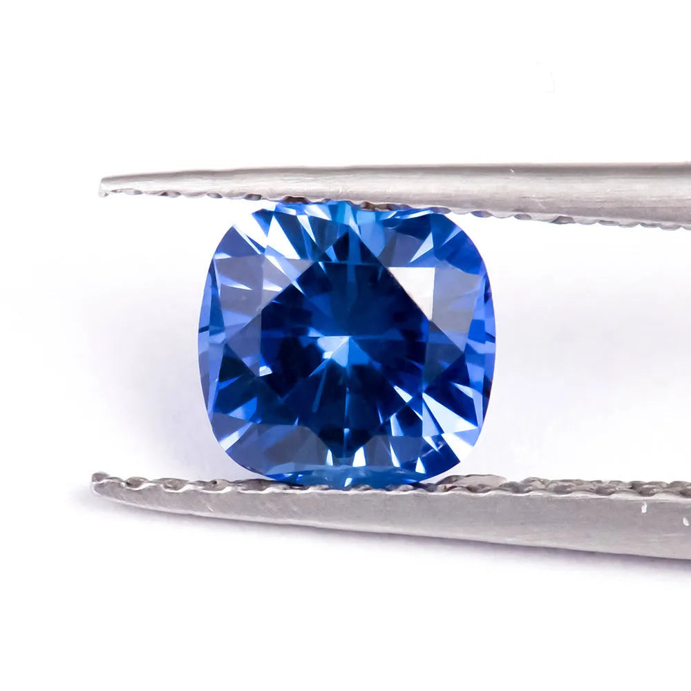 Royal blue loose cultured gemstone in heart, round, and pear shapes on a grey background.