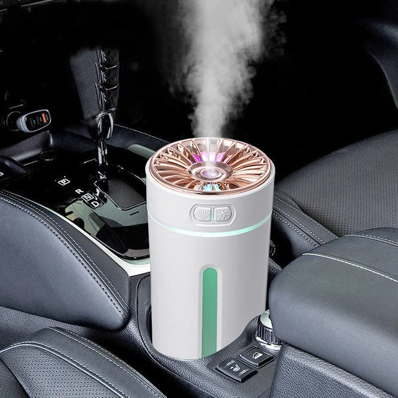Black portable ultrasonic humidifier with colourful LED lights, shown next to a USB cable on a desktop.