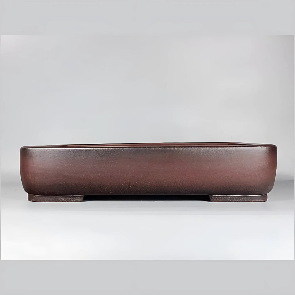 Handmade antique-style rectangular purple clay flower pot on a wooden surface.