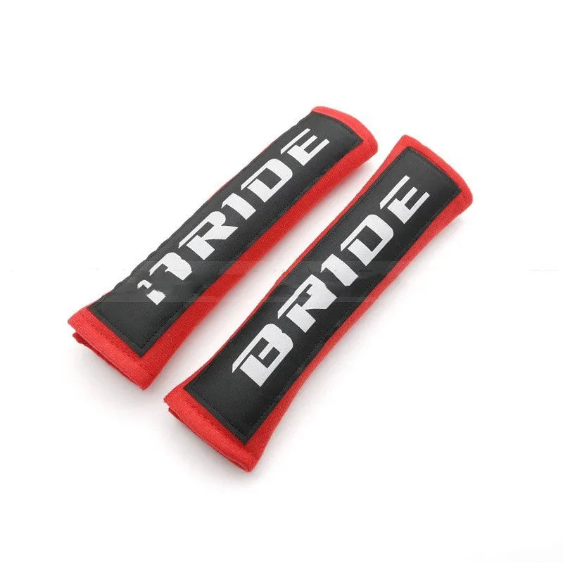 Pair of black cotton seat belt shoulder sleeves with embroidery, shown next to a car seat.