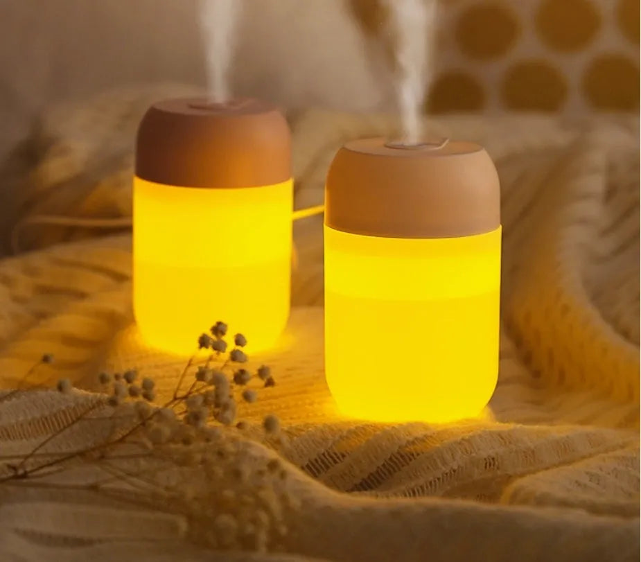 Small white cylindrical USB-powered mini humidifier on a wooden desk.