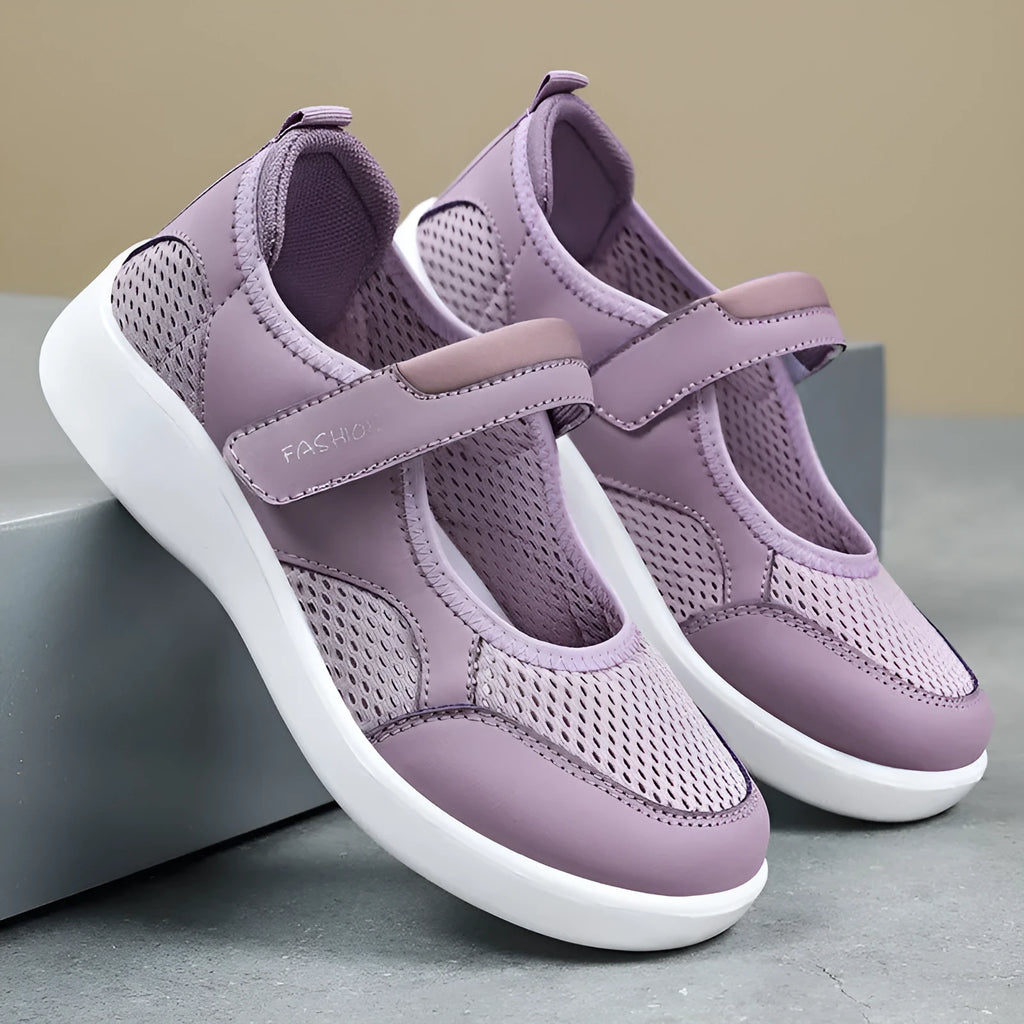 Women's grey casual slip-on shoe with mesh upper and Velcro strap on a flat sole.