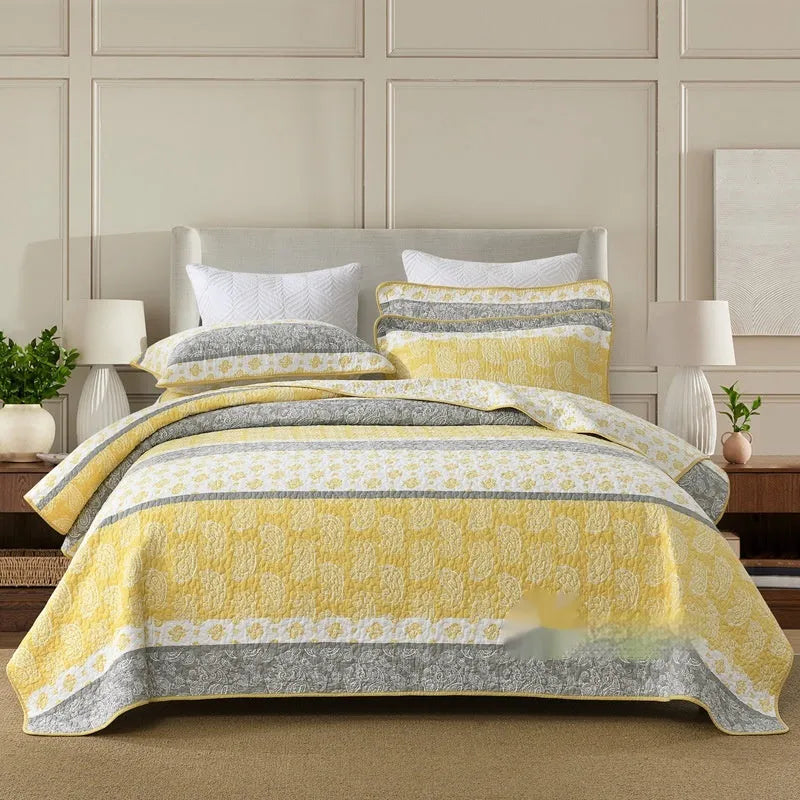 Quilted pure cotton bed cover set with printed pattern on a bed, includes two matching pillowcases.