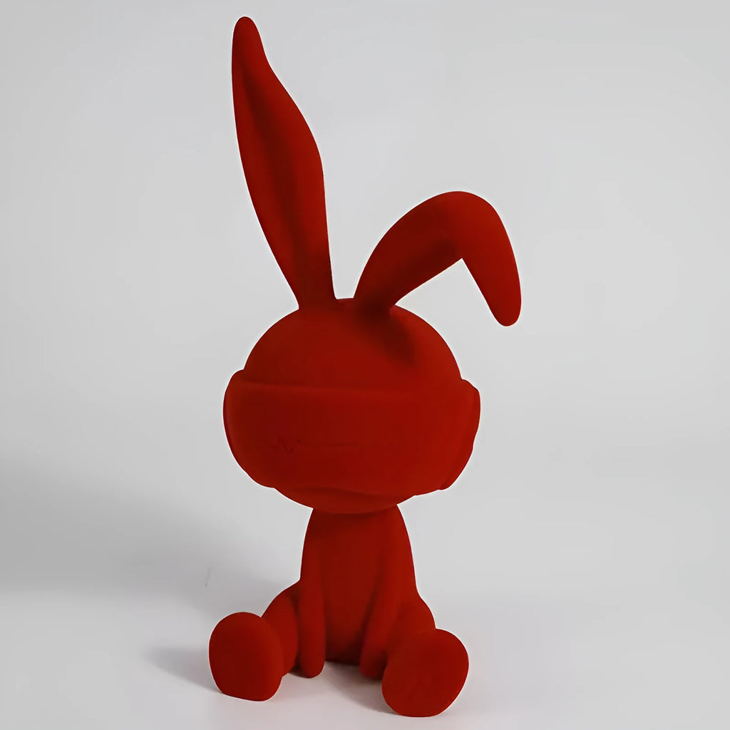 Green resin blindfold rabbit table ornament on a wooden surface.