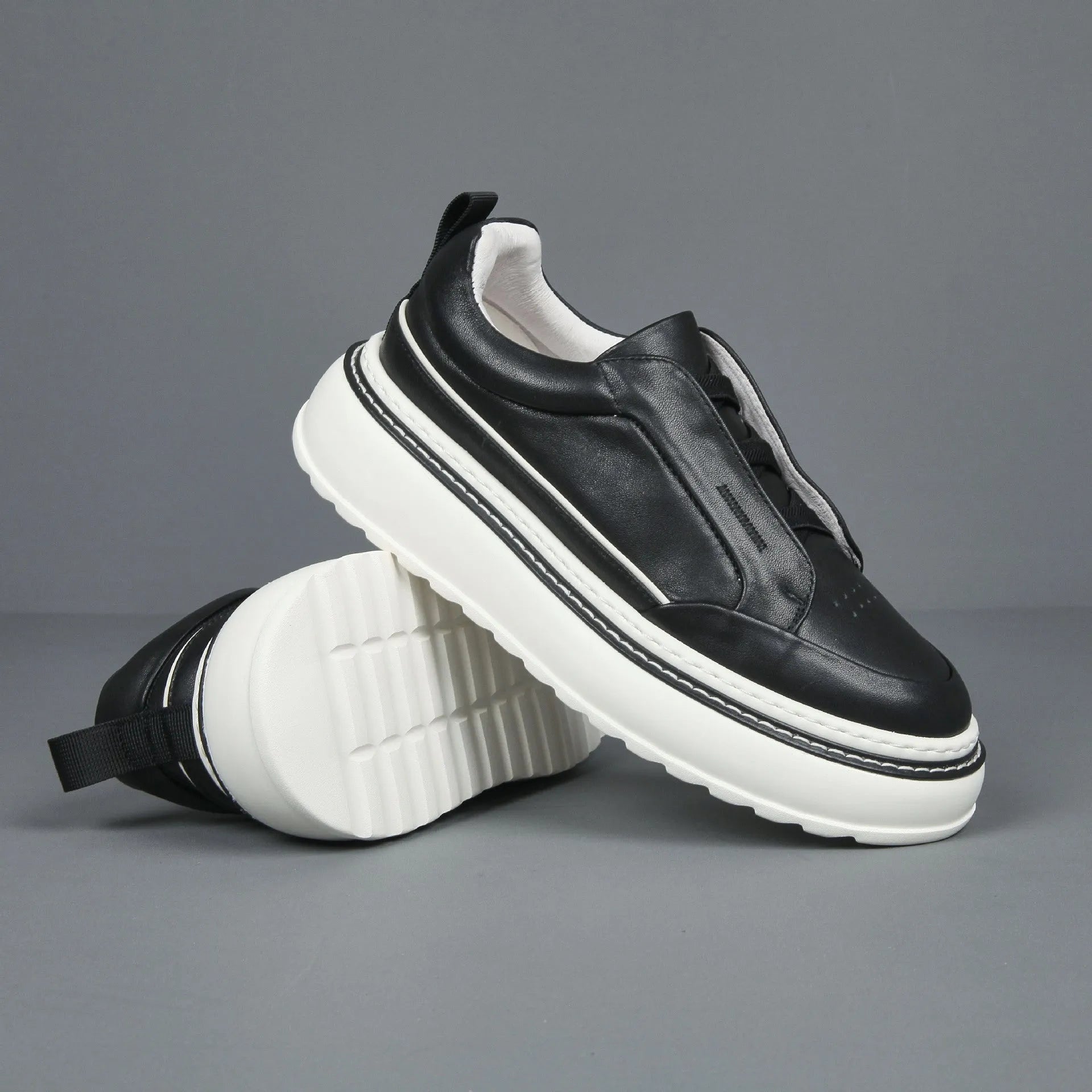 Black leather low-top slip-on sneaker with elastic sides and foam sole on white background