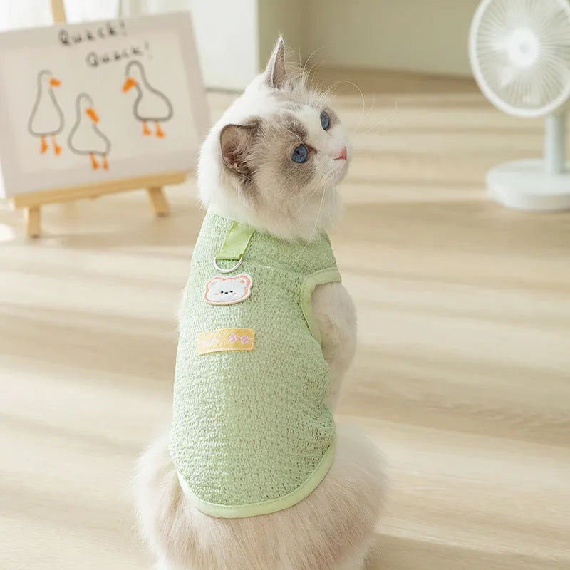 Green knitted cat clothes with a hollowed-out design and a cartoon bear patch.