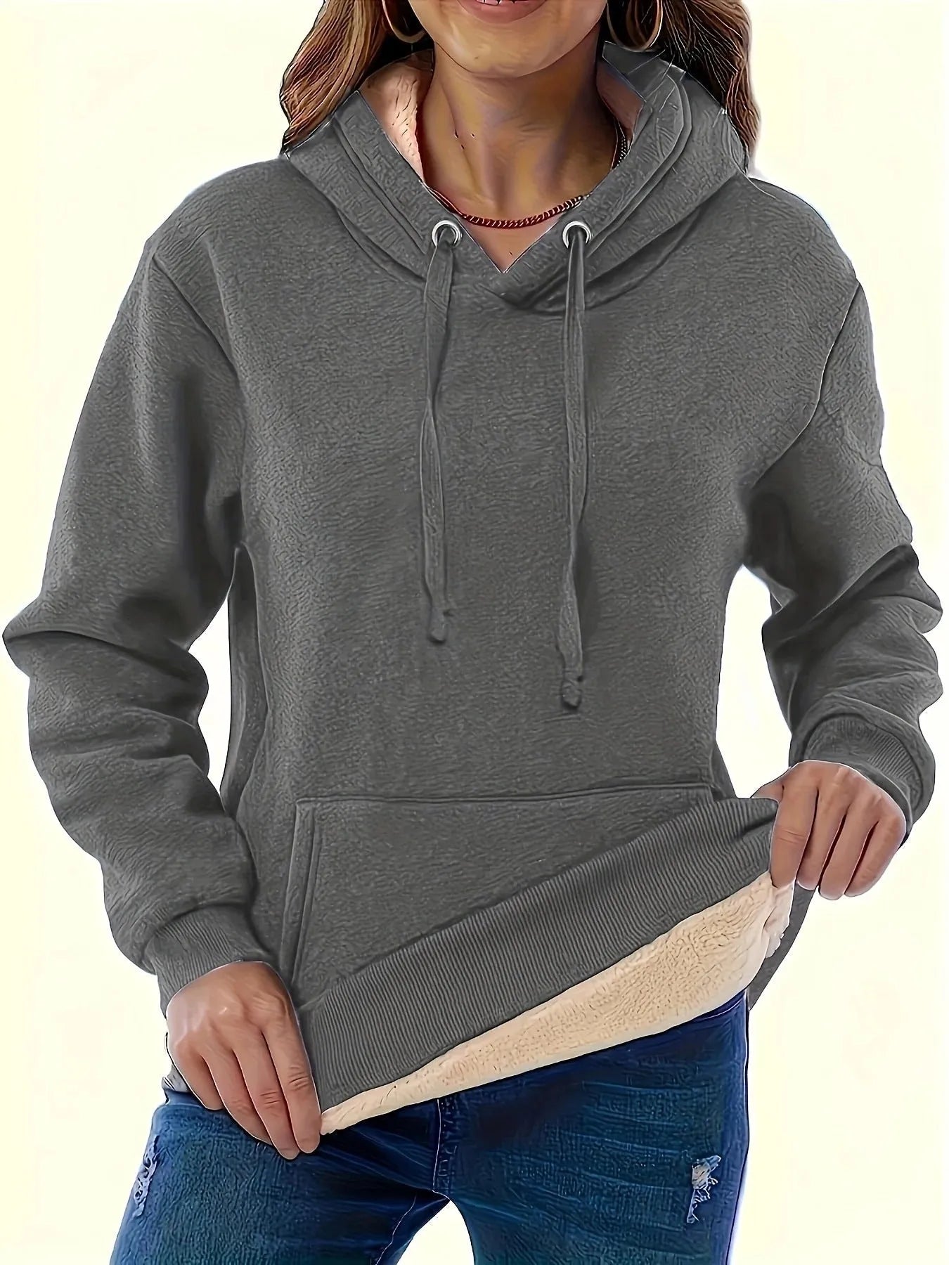 A woman wearing a loose thick black hooded sweater with side pockets and a 3D textured pattern.