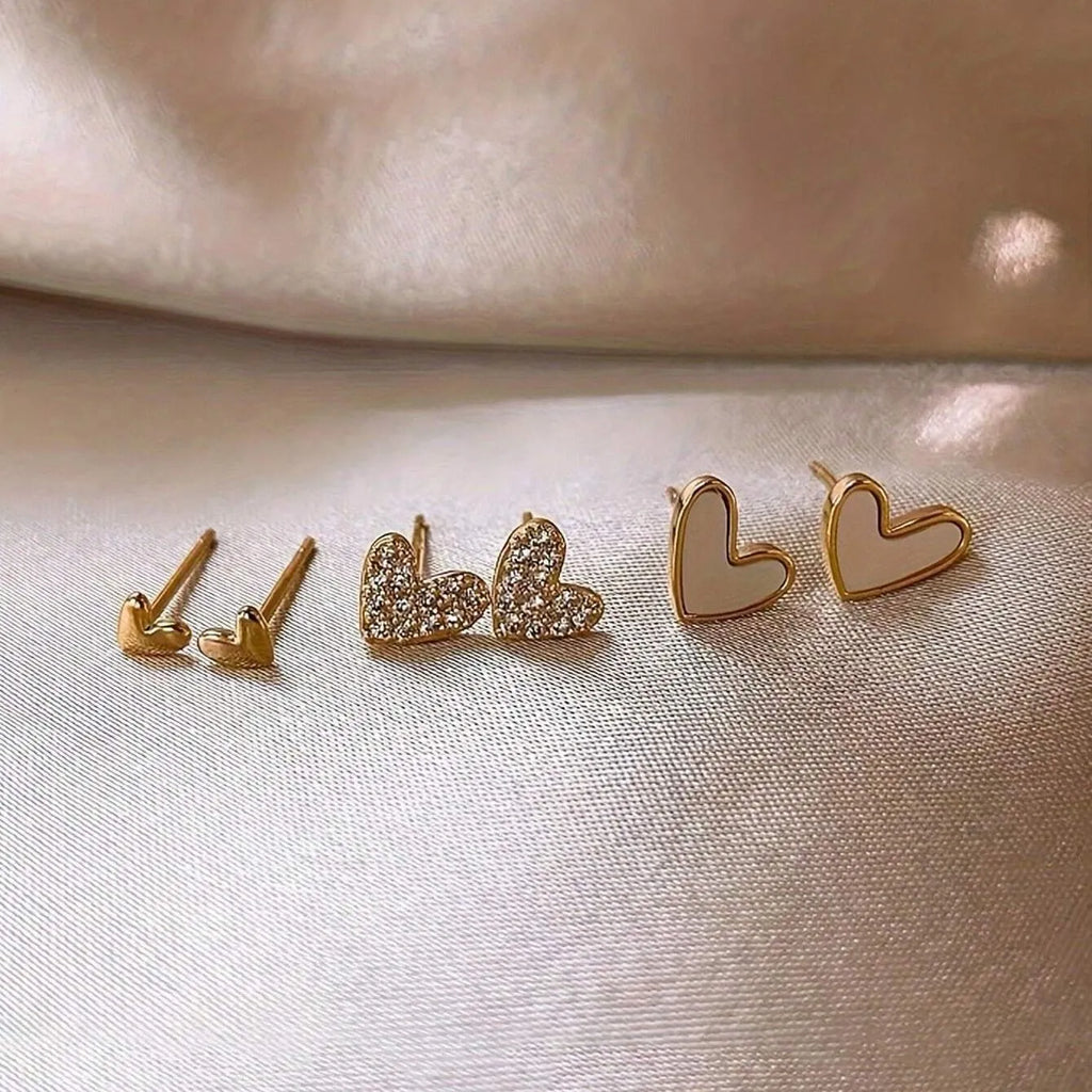 Three pairs of heart-shaped earrings with electroplated alloy construction in gold, black, pink and black-white colours
