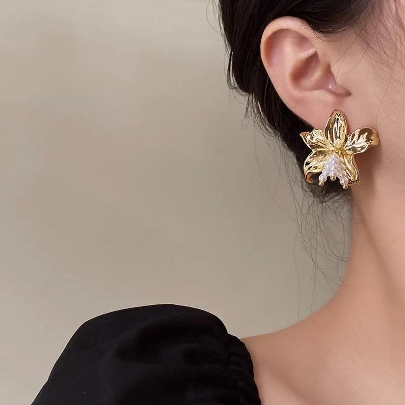 Gold H1795 metal flower earrings with a pearl centre, showing exaggerated floral shape and niche style.