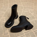 Black women's flat-heel ankle boots with a round toe and back zipper on a white background