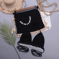 Women's handmade lace-up split swimsuit in black with removable short skirt laid flat.
