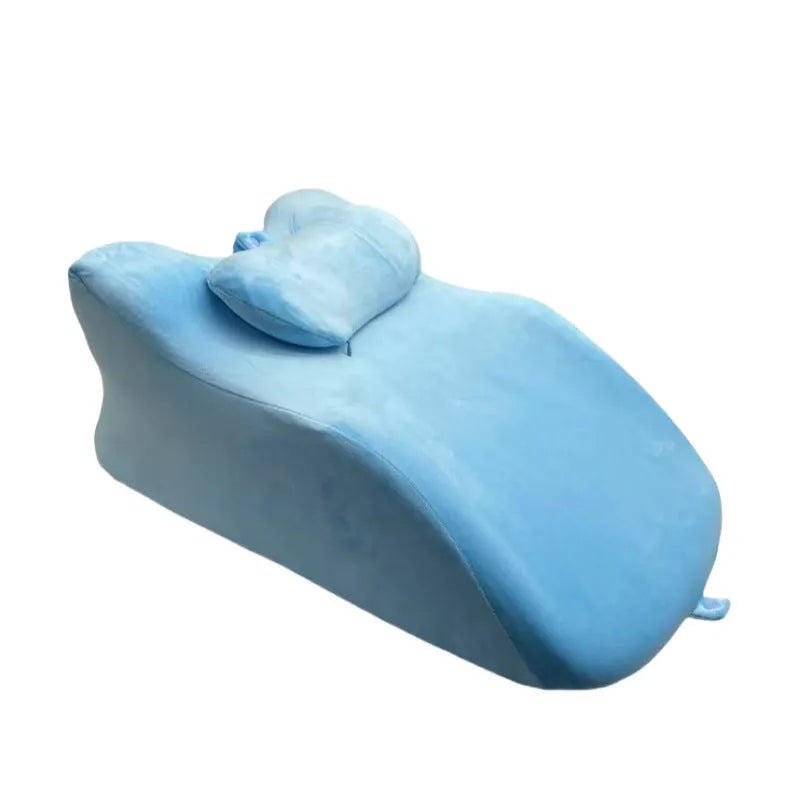 A stomach sleeper pillow shown in light grey, designed for reading or phone use in a prone position.