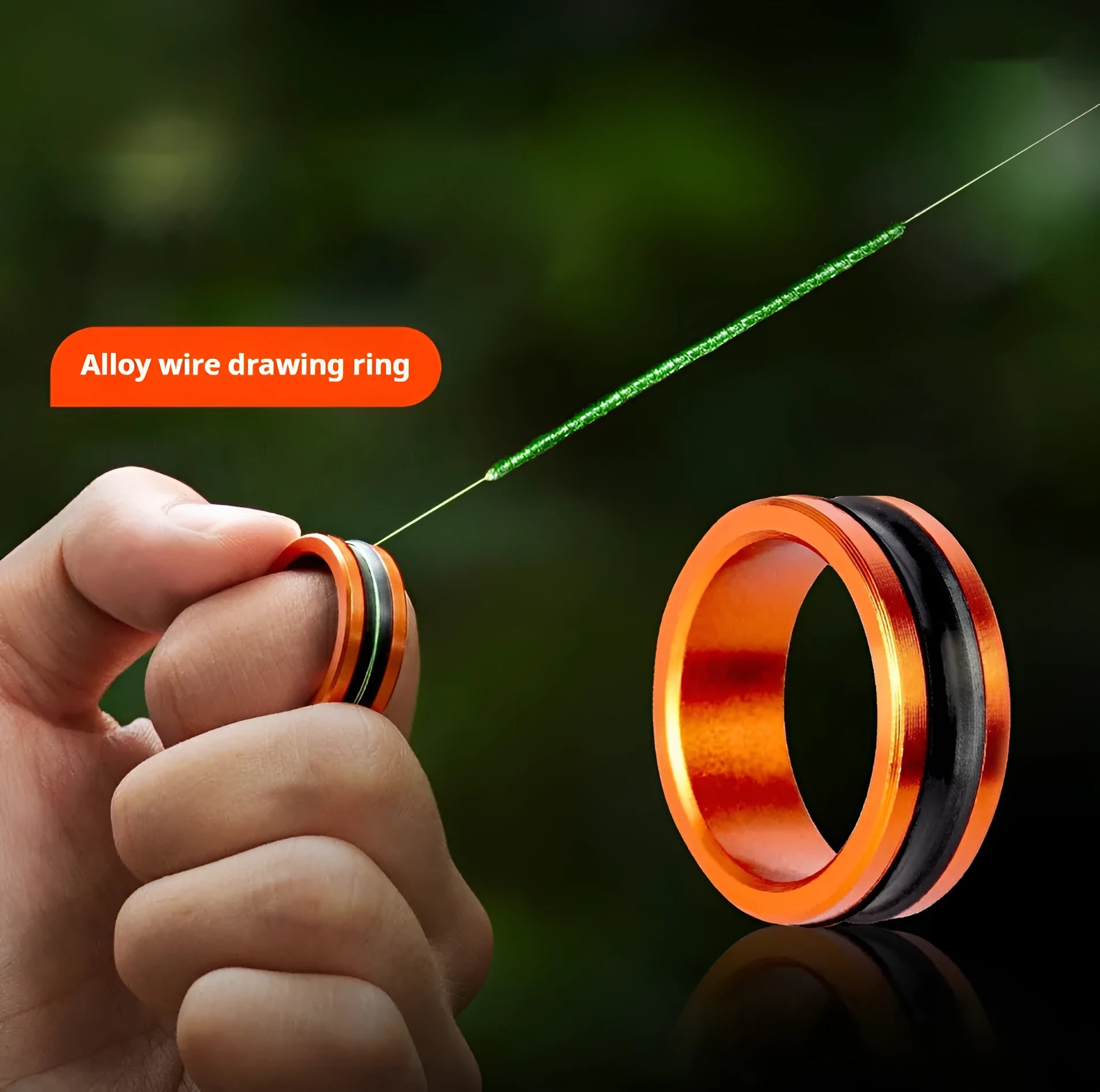Orange and silver alloy fishing hand guard pull loop tool on a dark background.