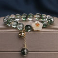 Green Phantom quartz crystal bracelet with white jade flower on a plain background
