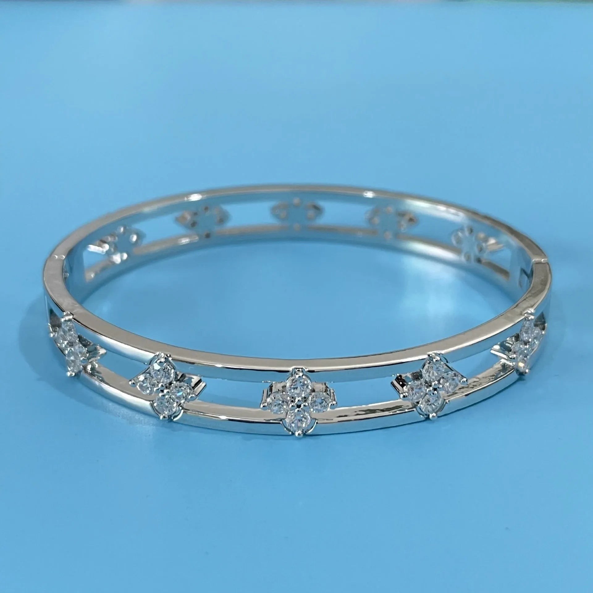 Women's hollow bracelet with four-leaf clover charm and zircon inlay detailing on copper-plated gold